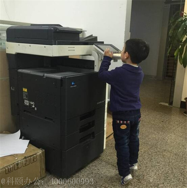 我們家小小帥掂著小腳在操作著柯尼卡美能達(dá)復(fù)印機(jī)的樣子-科頤辦公